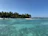 Children excitedly exploring a tropical beach with turquoise waters under bright blue skies.