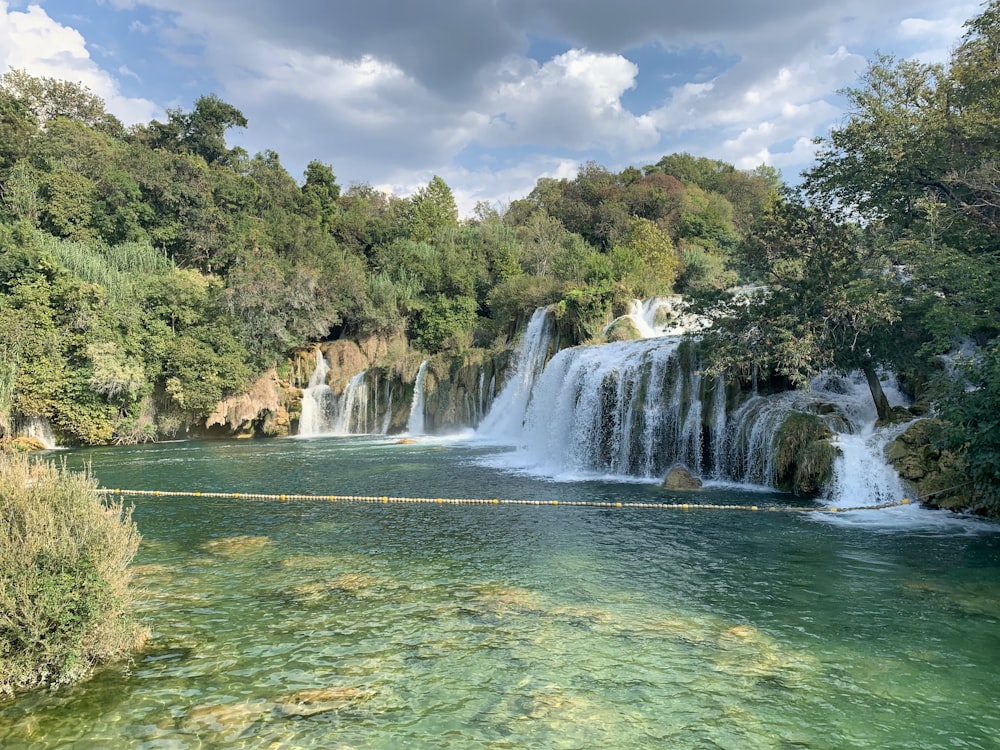 waterfalls in the middle of green trees during daytime