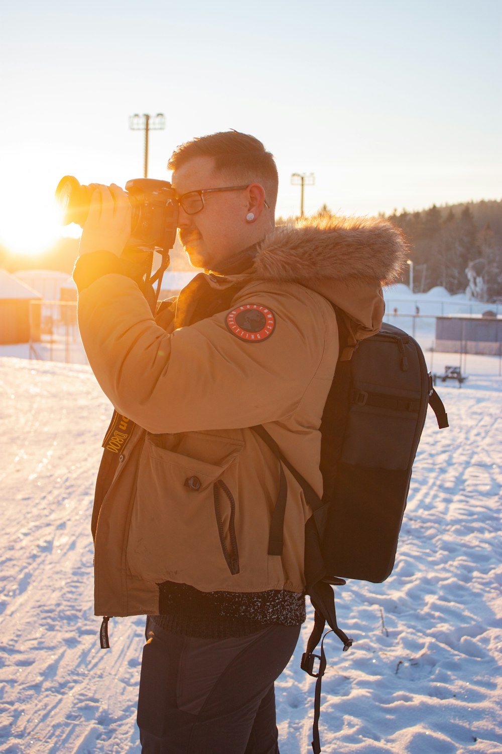 man in brown jacket holding black dslr camera