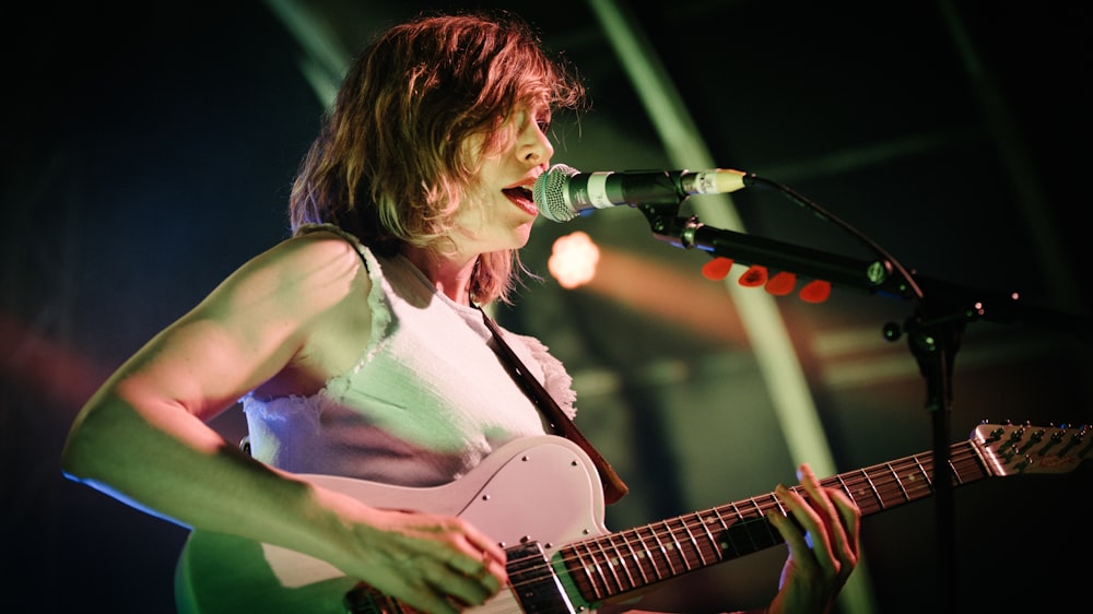 woman in white tank top playing guitar