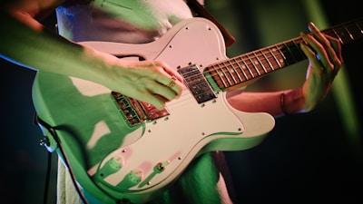 person playing white and brown stratocaster electric guitar