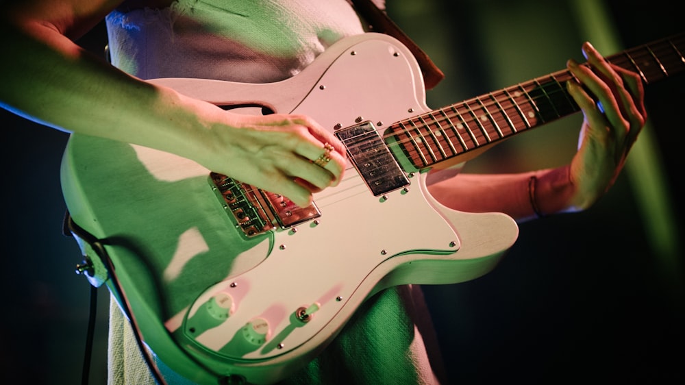 흰색과 갈색 스트라토캐스터 일렉트릭 기타를 연주하는 사람