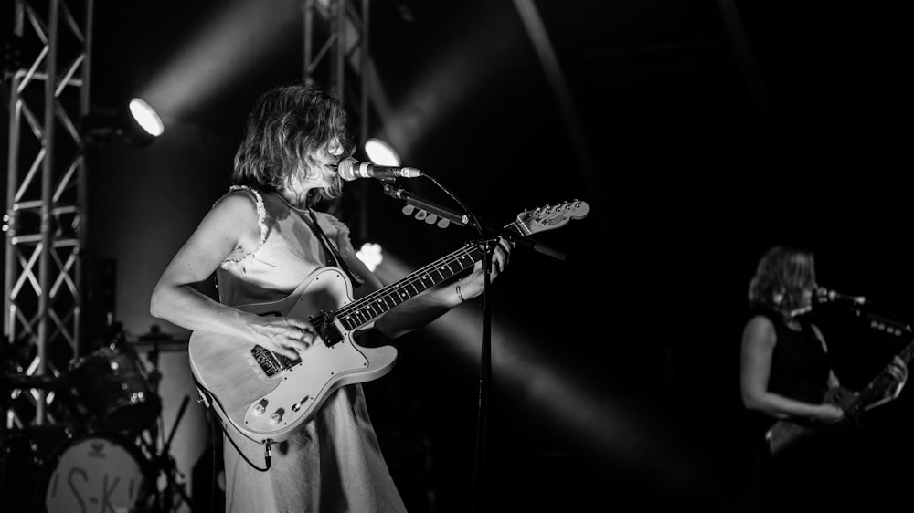 grayscale photo of man playing electric guitar