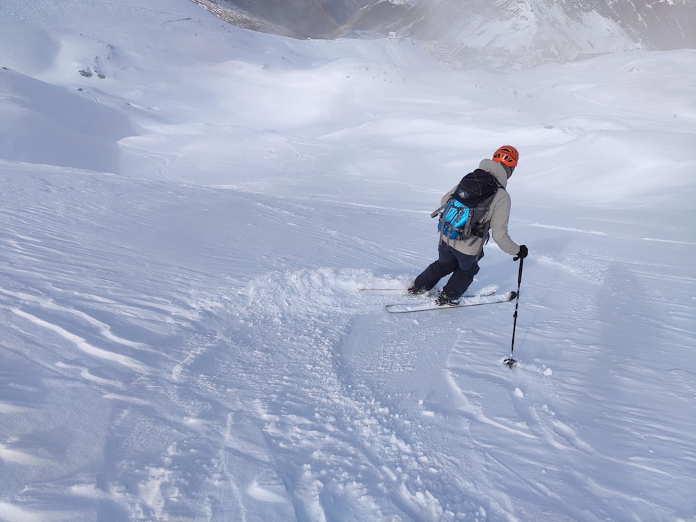 man in blue jacket and black pants riding ski blades on snow covered ground during daytime