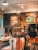 A rustic store interior with wooden walls and stylish lighting. The wall features artistic graphics and text. Clothing items such as t-shirts and hats are neatly displayed on racks. The atmosphere feels laid-back and trendy.