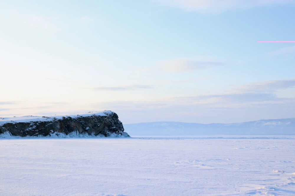 black rock formation on sea under white clouds during daytime