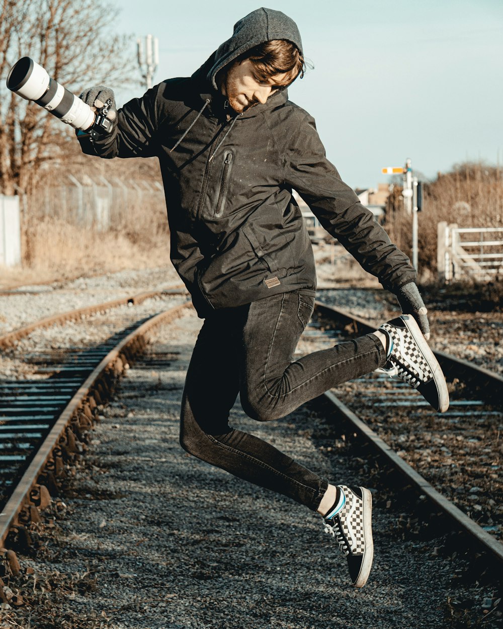 man in black leather jacket and black pants sitting on train rail during daytime