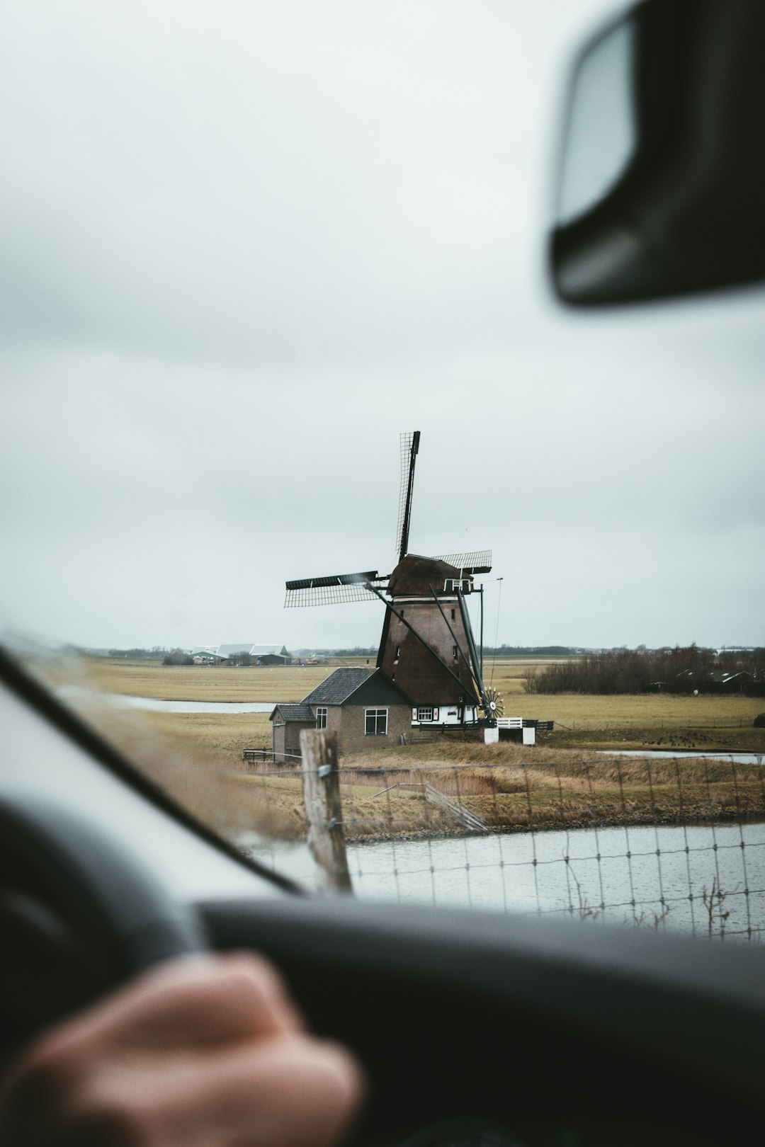 white windmill on brown field under white sky during daytime