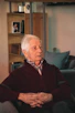 A calm elderly man reviewing printed probate documents in his cozy living room, looking relieved and satisfied.