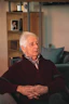 A calm elderly man reviewing printed probate documents in his cozy living room, looking relieved and satisfied.