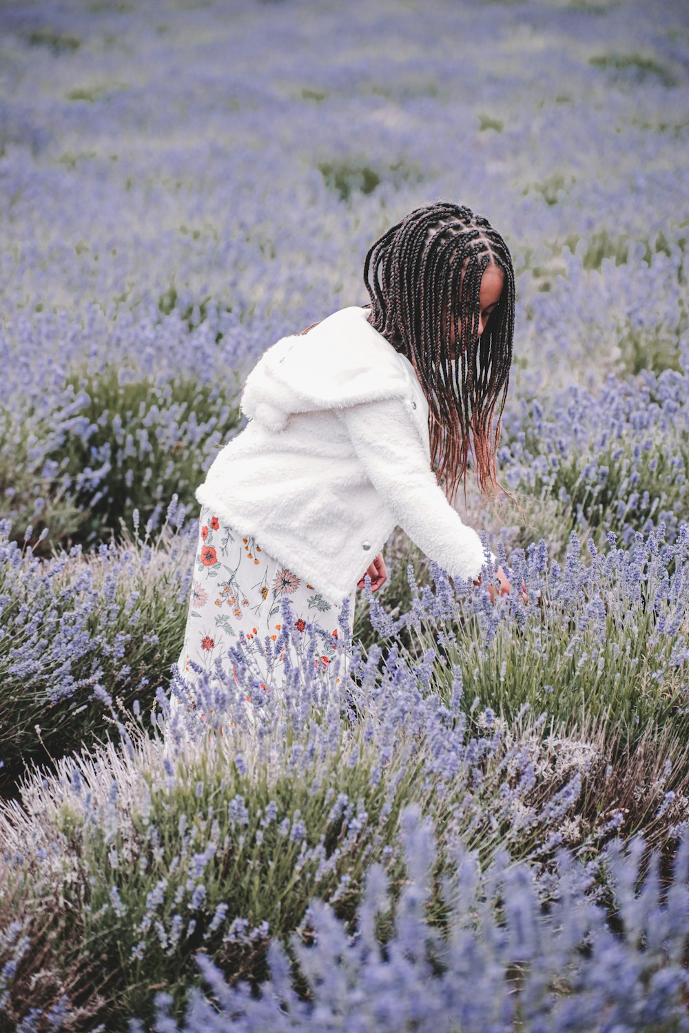 girl in white jacket standing on green grass field during daytime