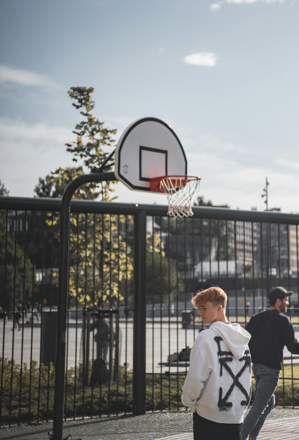 man in white shirt standing near basketball hoop