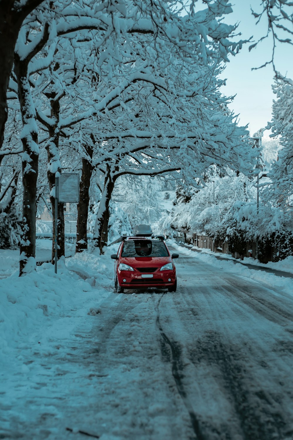 red car on road covered with snow during daytime
