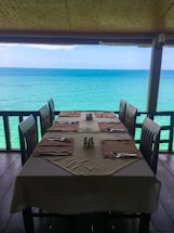 A cozy dining table set with fresh seafood dishes overlooking the Galápagos coastline at sunset