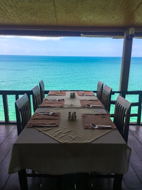 A cozy dining table set with fresh seafood dishes overlooking the Galápagos coastline at sunset
