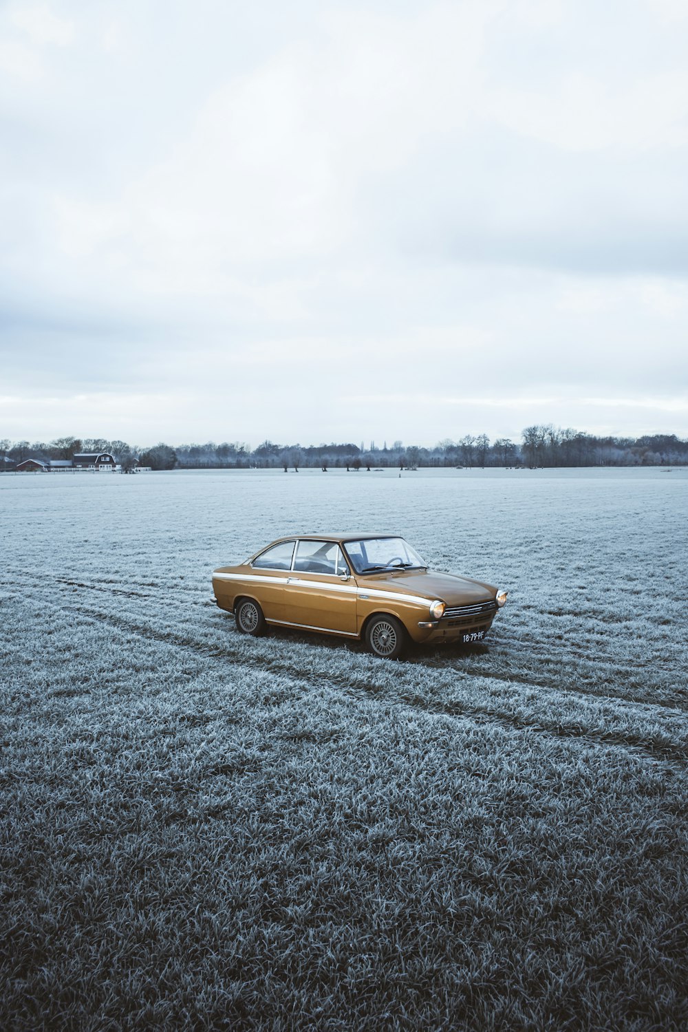 yellow car on gray sand near body of water during daytime