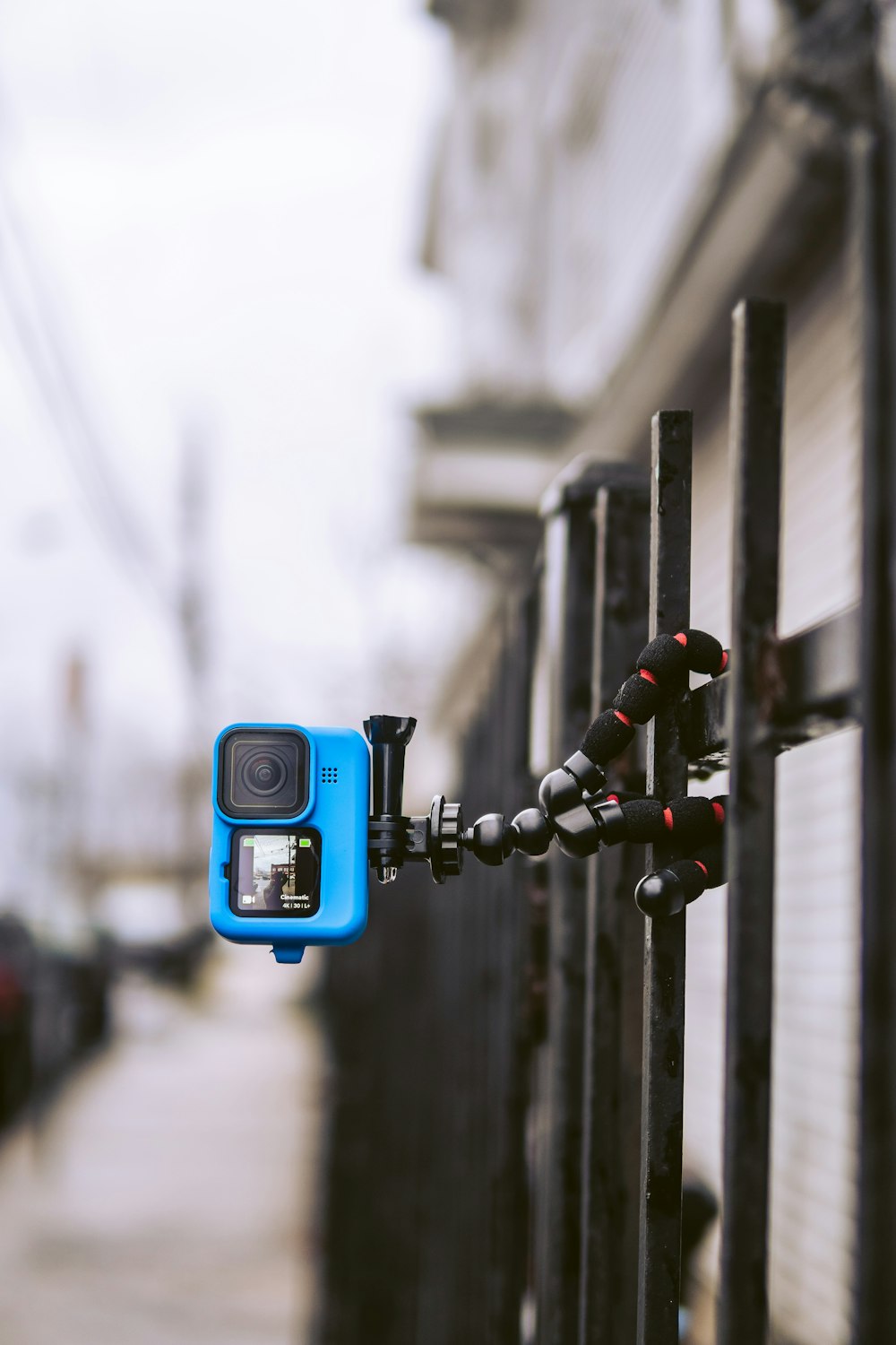 blue and black camera on black metal fence