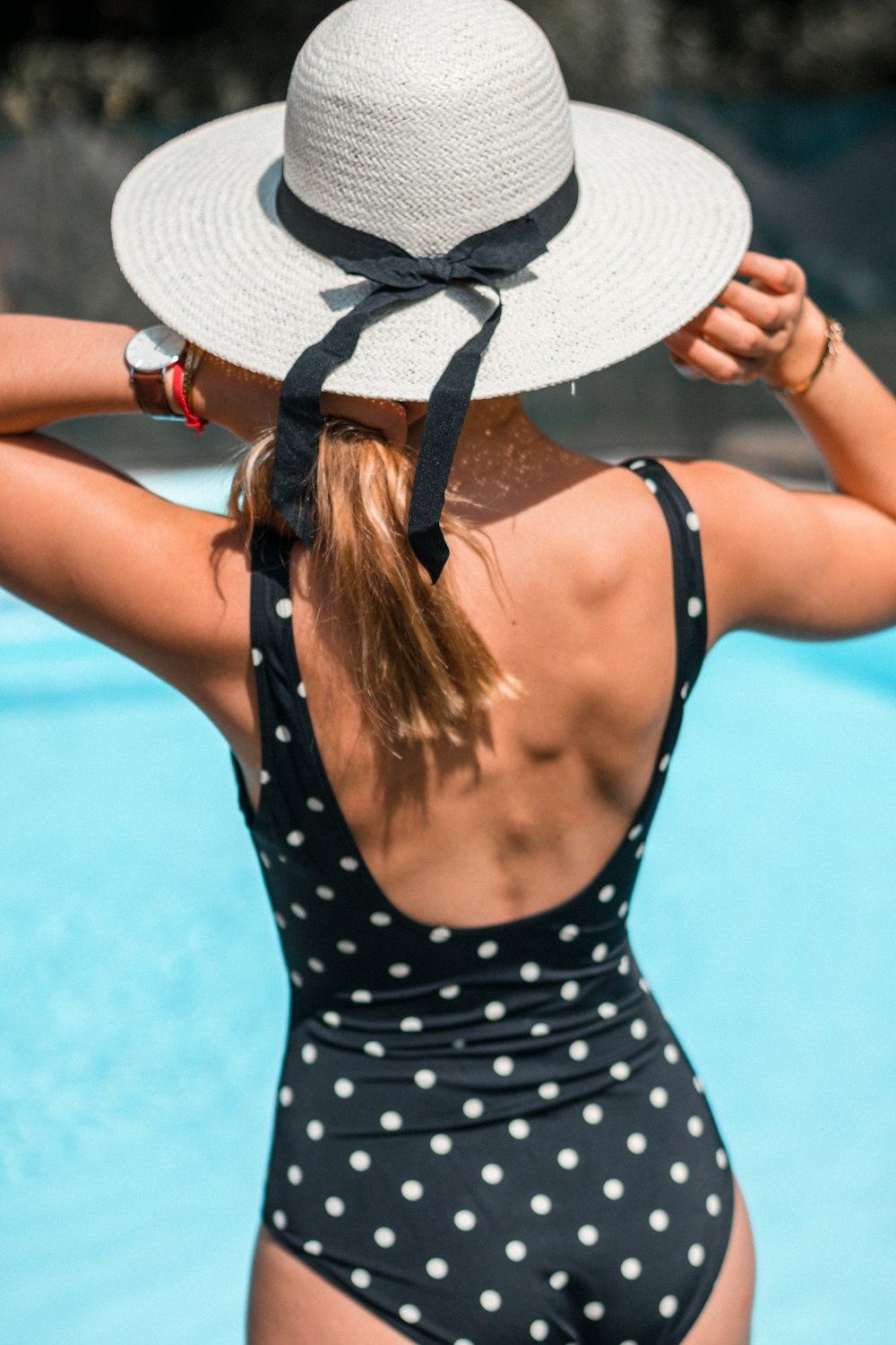 woman in black and white polka dot spaghetti strap top wearing white sun hat