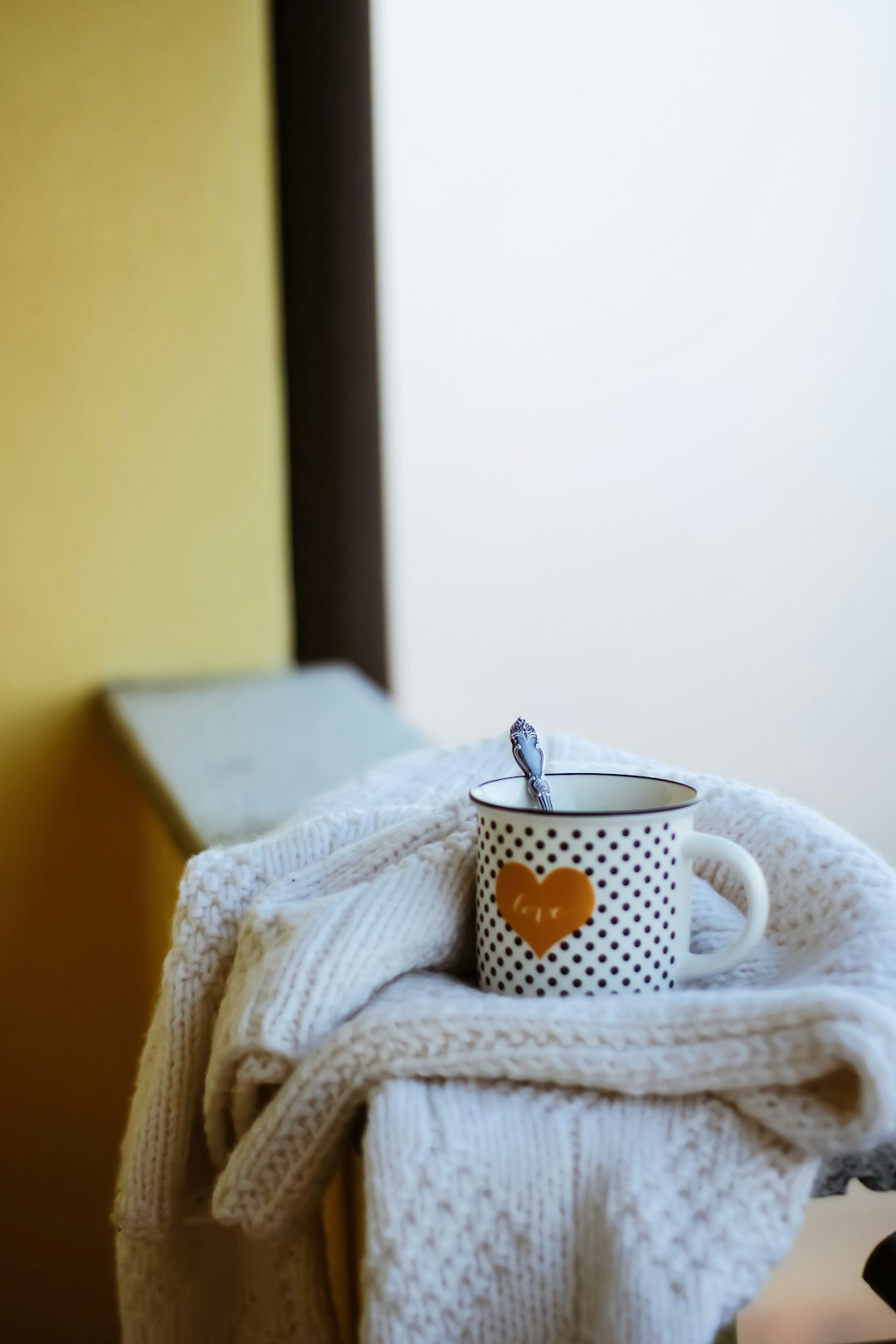 white and yellow polka dot ceramic mug on white knit textile