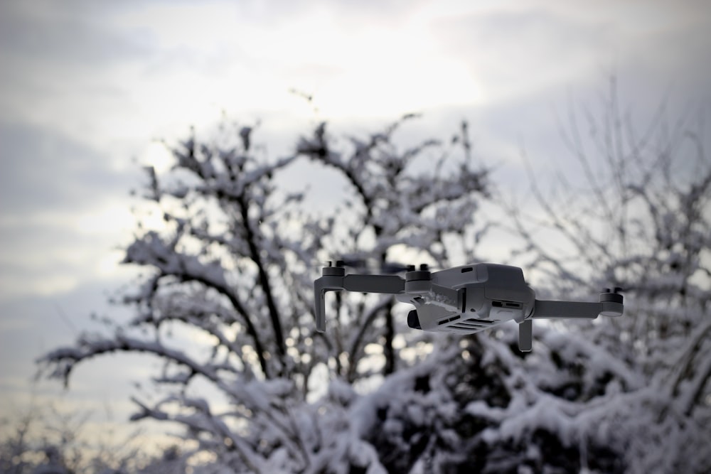 black drone flying over snow covered trees during daytime