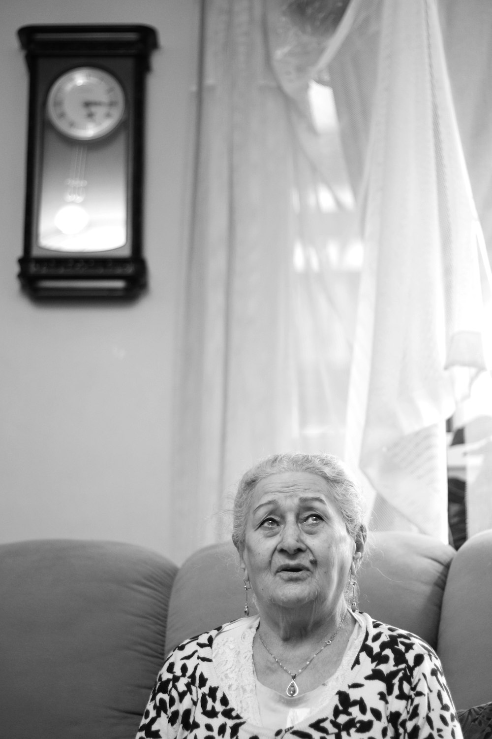 grayscale photo of woman sitting on sofa
