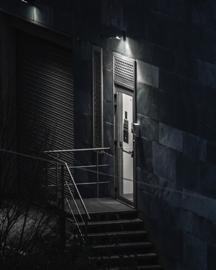 A matte-black and gold-leaf themed cinematic shot of a hidden underground club entrance glowing faintly in the night.