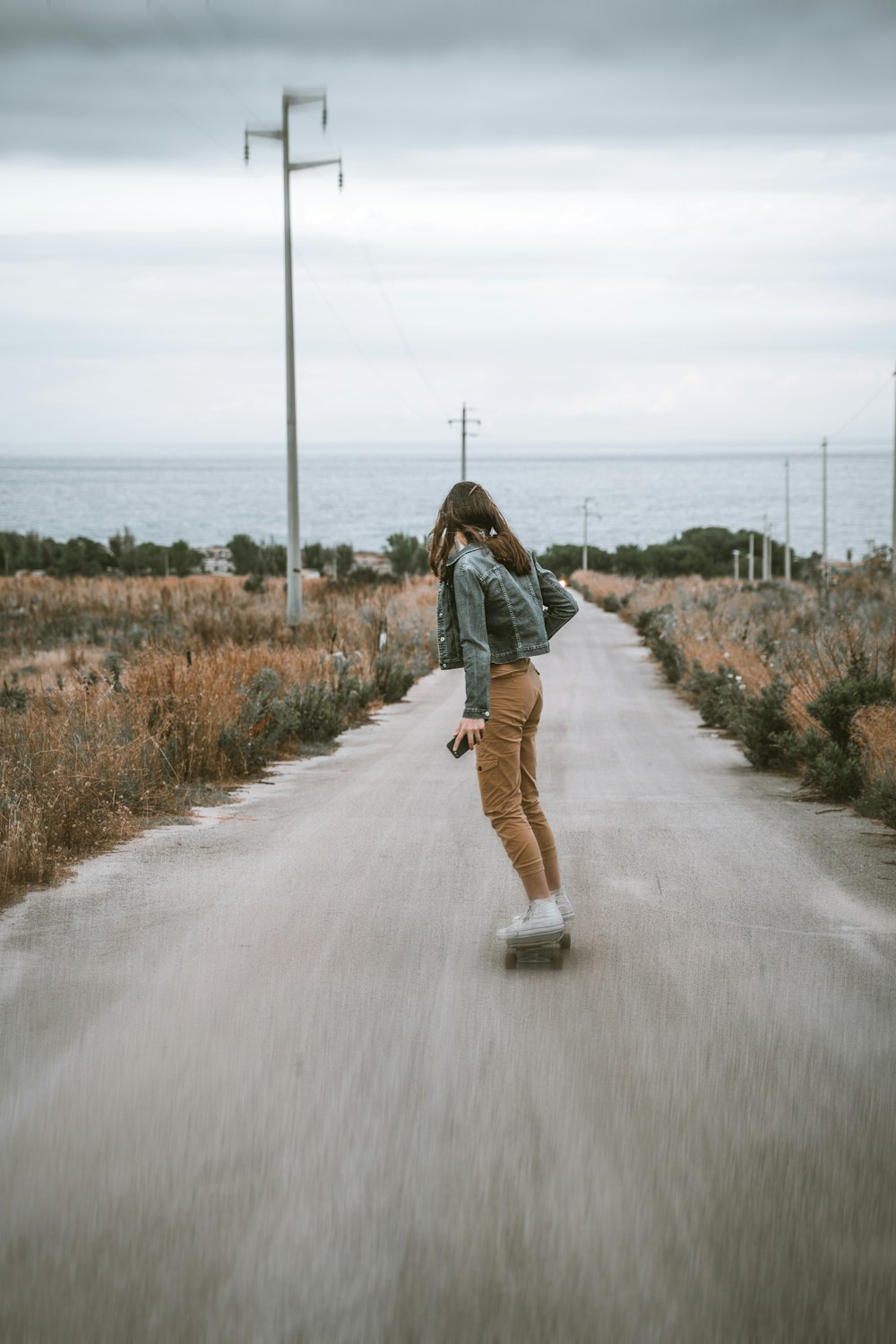 woman in blue denim jacket walking on road during daytime