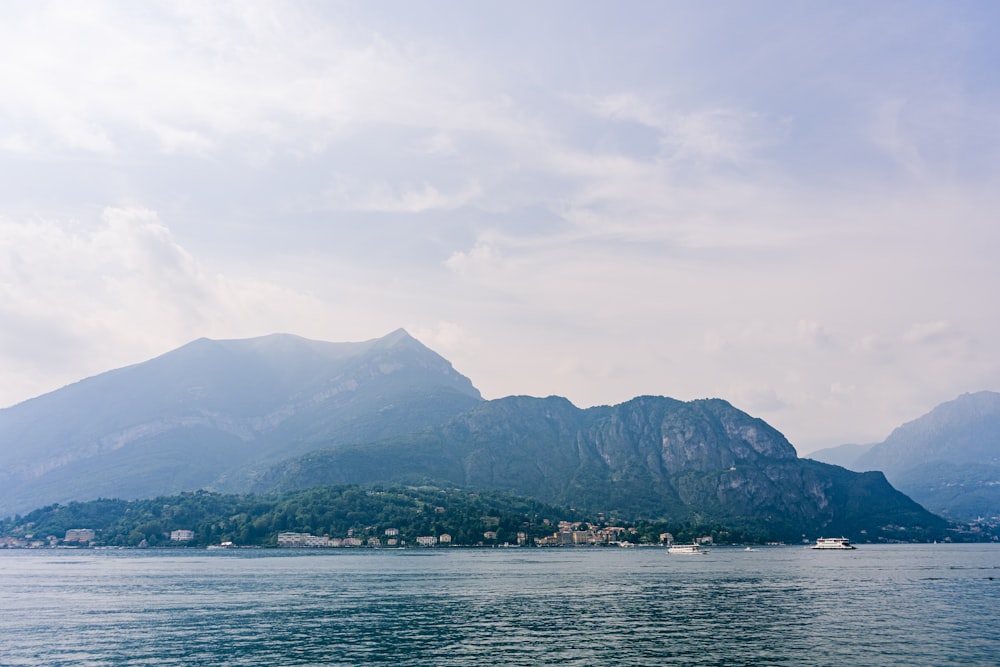 green mountain beside body of water under cloudy sky during daytime