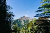 A picturesque mountain landscape with lush greenery and a clear blue sky.