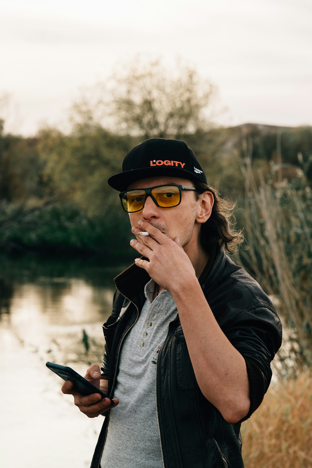 man in black leather jacket and black fitted cap smoking cigarette