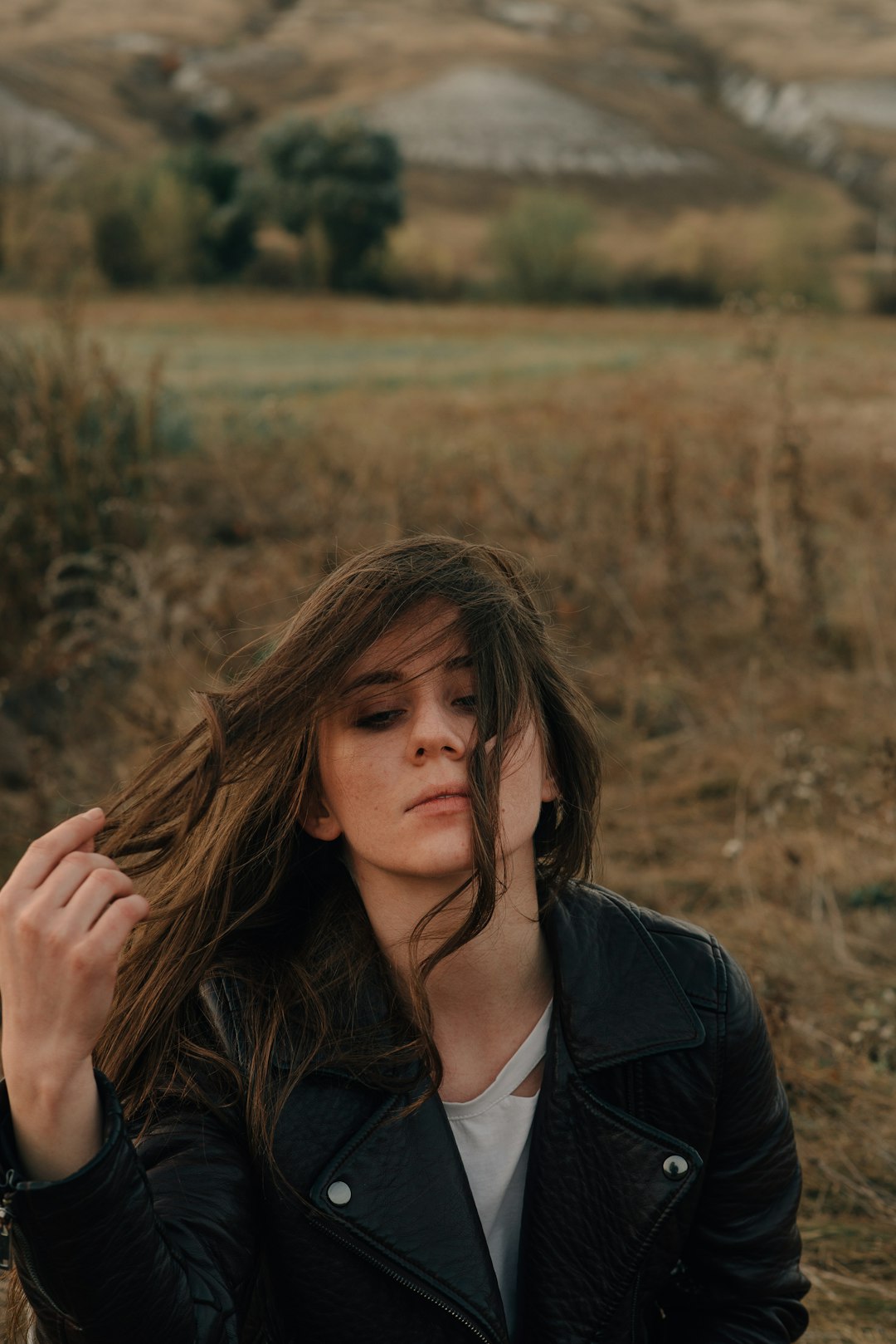 woman in black coat standing on brown grass field during daytime