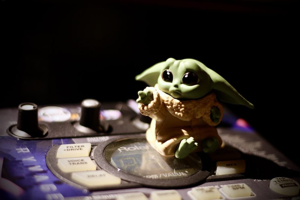 Figura de rana verde en controlador de DJ negro y gris