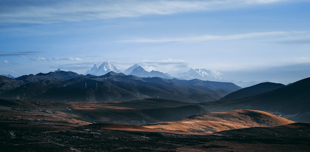 brown and black mountains under white clouds and blue sky during daytime