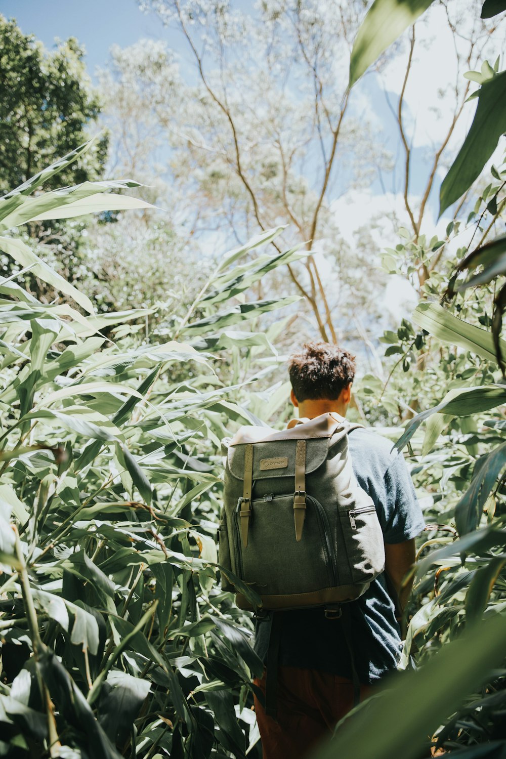 man in gray shirt carrying green backpack