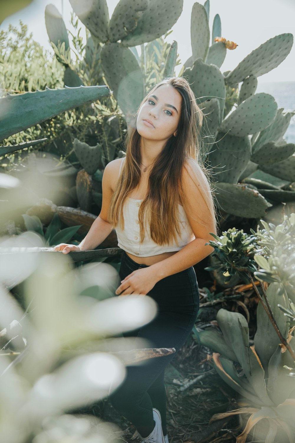 woman in white tank top sitting on green plants