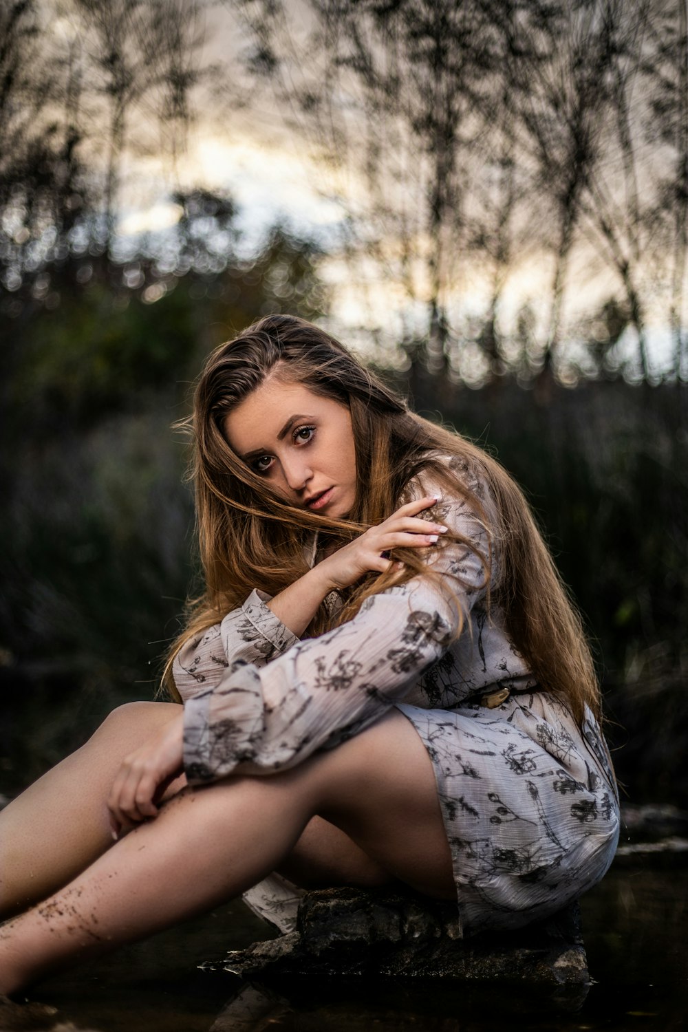 mulher no vestido floral branco e preto sentado no banco de madeira marrom