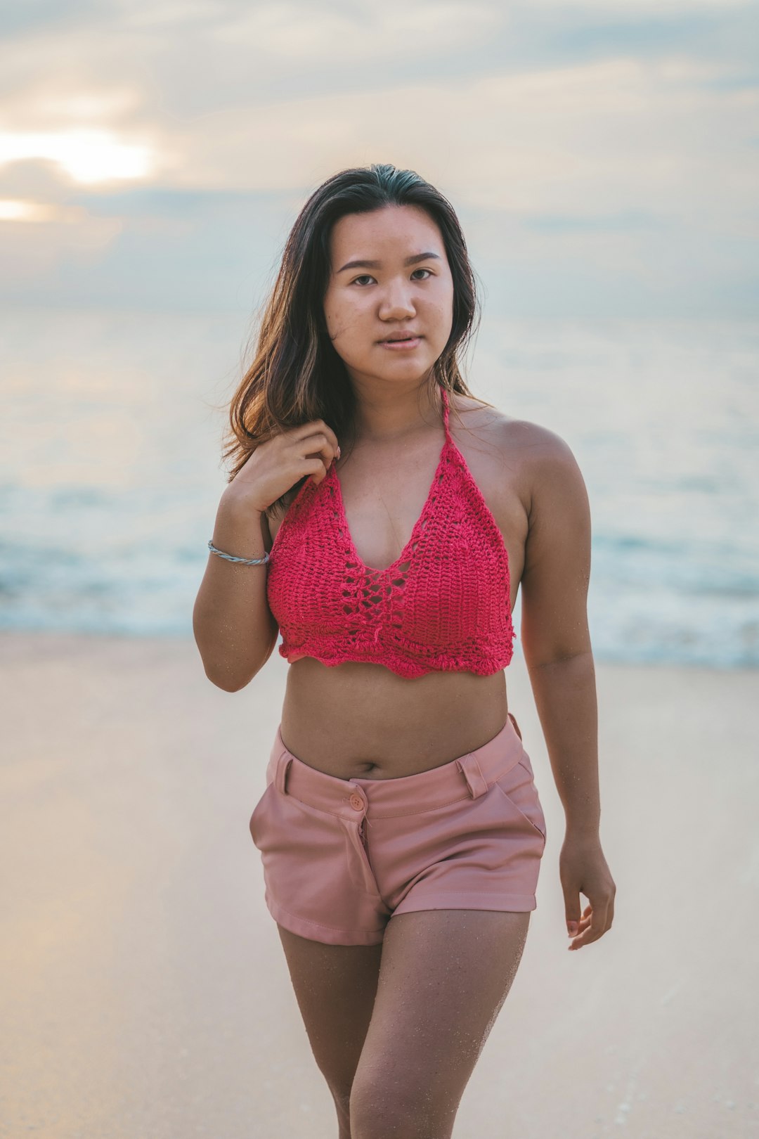 woman in pink bikini top and brown shorts standing on beach during daytime