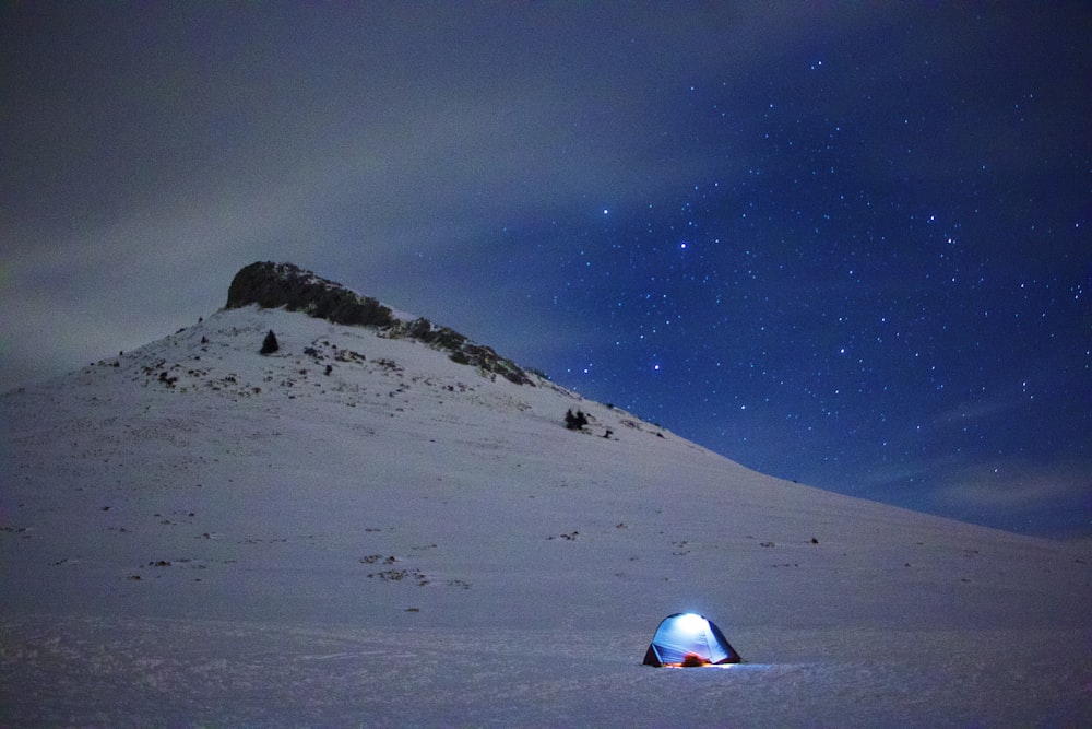 weiß-rotes Zelt tagsüber auf schneebedecktem Boden unter blauem Himmel