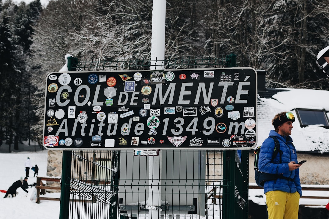 man in blue jacket standing near black metal fence