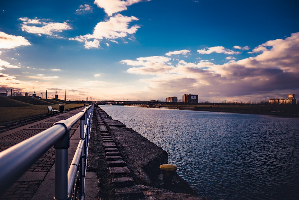 body of water near city buildings under blue and white sunny cloudy sky during daytime