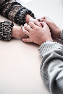 person in gray long sleeve shirt holding persons hand