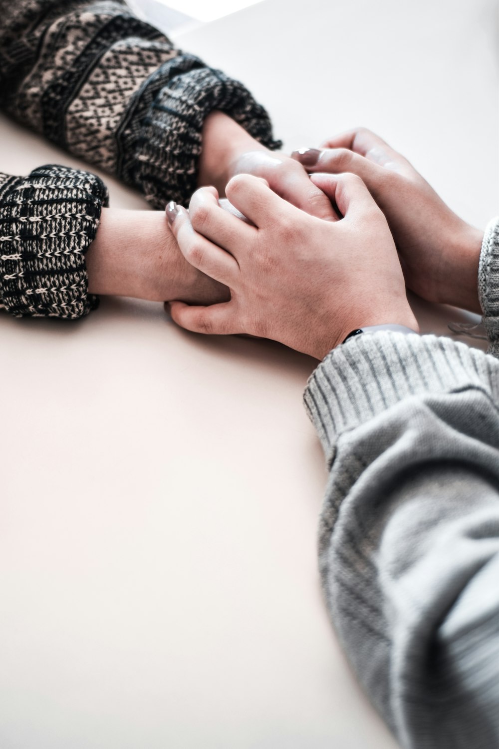 persona in camicia grigia a maniche lunghe che tiene la mano delle persone