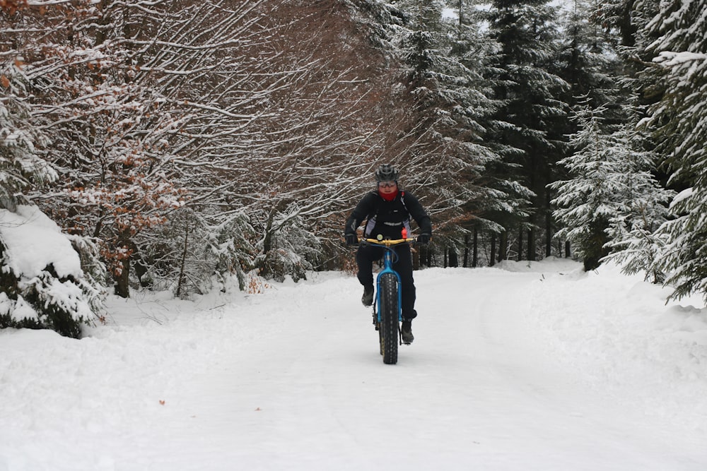 person in black jacket riding on black bicycle on snow covered ground during daytime