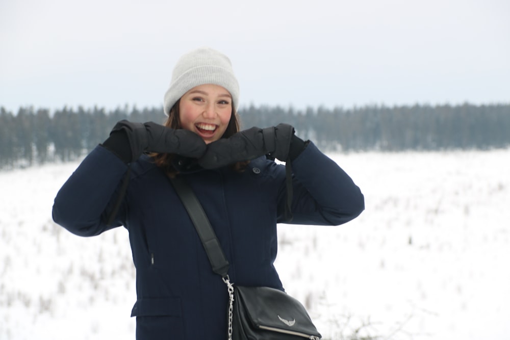 woman in black jacket and white knit cap standing on snow covered ground during daytime