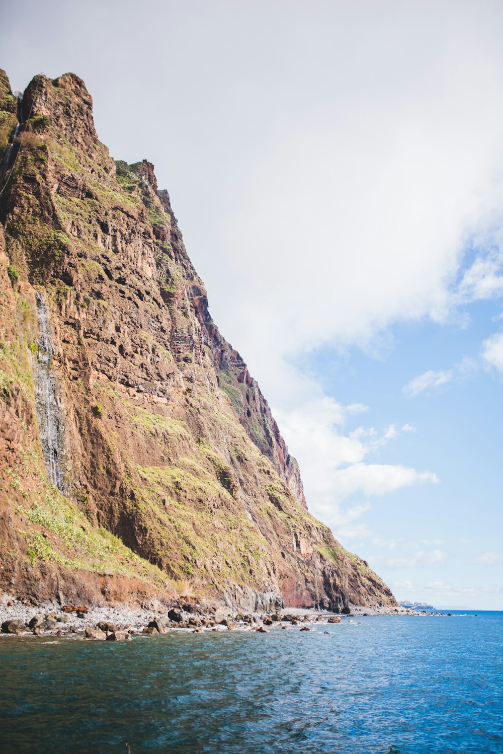 brown and green mountain beside body of water during daytime