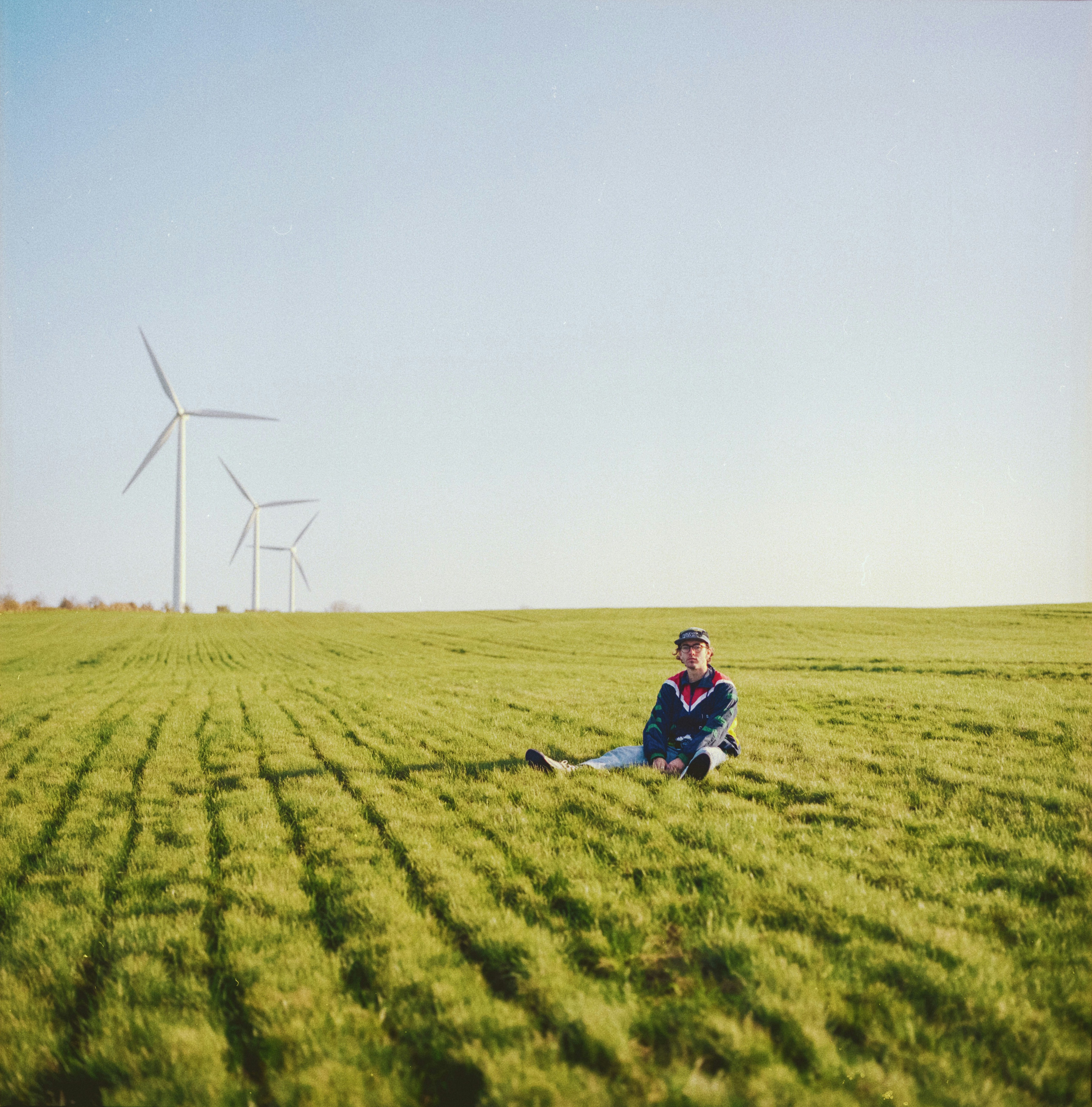 man in blue shirt and black pants sitting on green grass field during daytime