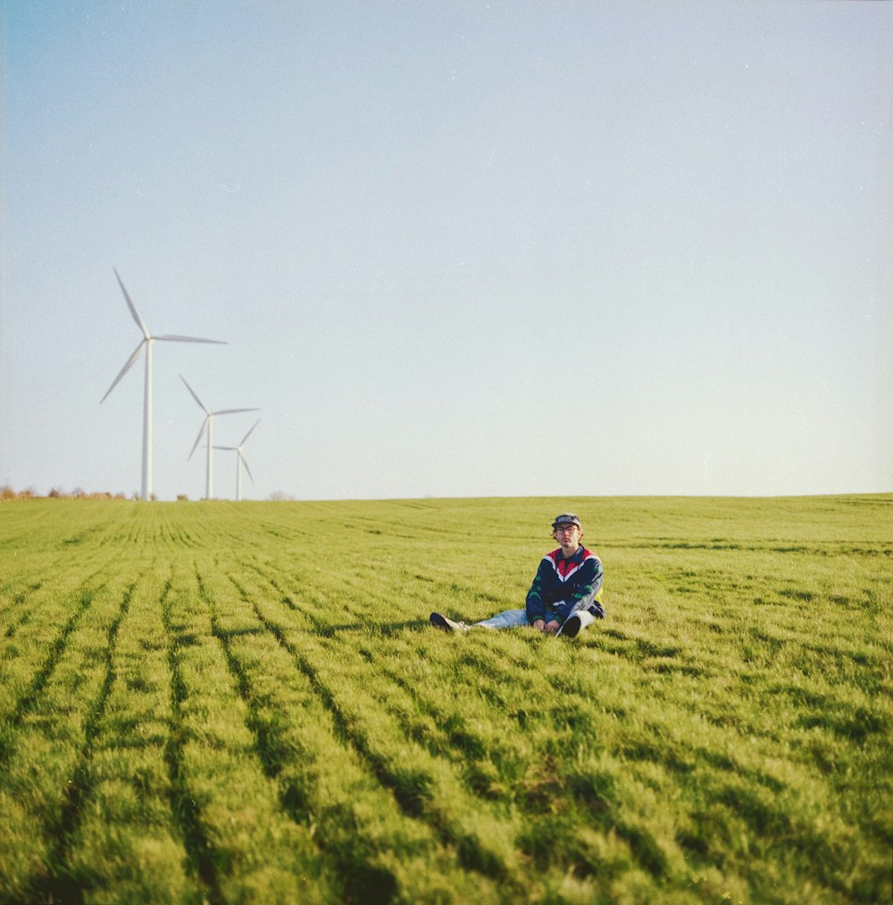 man in blue shirt and black pants sitting on green grass field during daytime