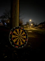 A view of the dartboard with dim bar lights and cold drinks placed on a nearby wooden table.