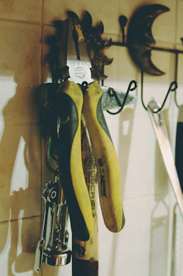 A close-up of adhesive hooks holding kitchen utensils against a vibrant tiled backsplash.