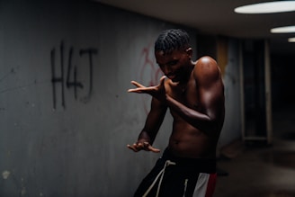 topless man in black and red shorts standing near gray wall